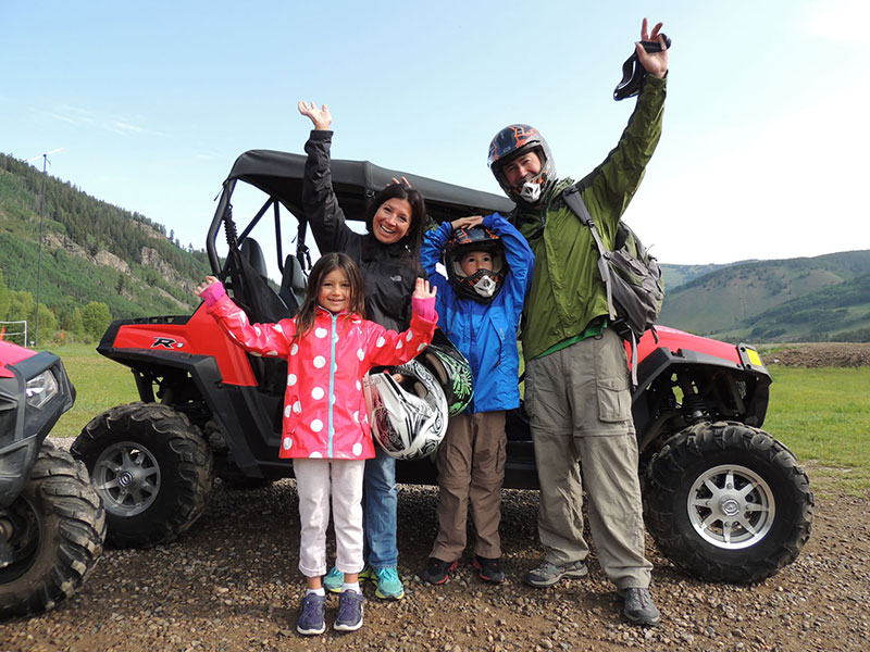 Family with hands in the air in front an ATV