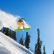 Snowboarder in the air off a jump with snow trailing behind him.